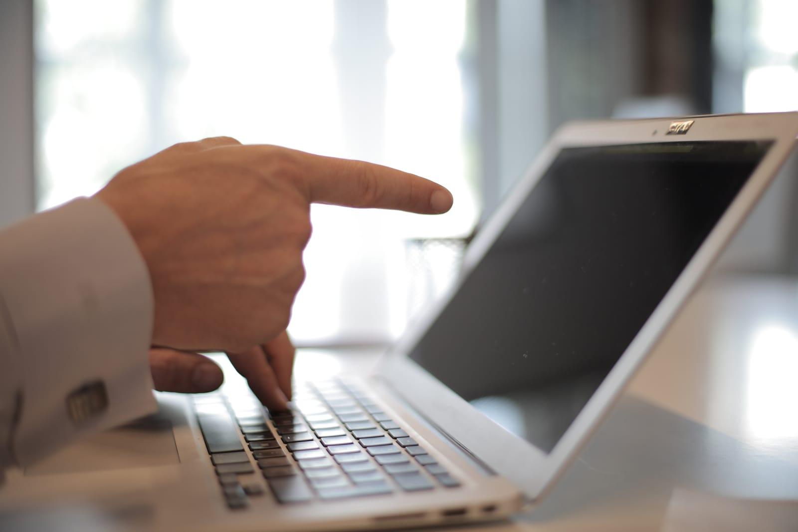 A person reviewing financial figures on a laptop at a bright desk